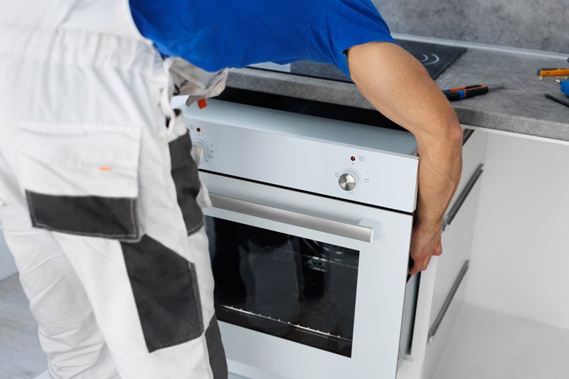 a man installs an oven after assembling the kitche